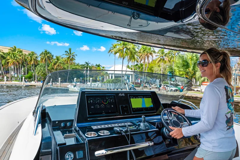  Yacht Photos Pics Woman steering 2024 Solaris Power 44 Open yacht, vibrant tropical backdrop.