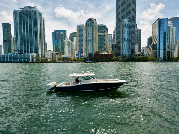  Yacht Photos Pics 2021 Scout 380 LXF boat cruising near city skyline.