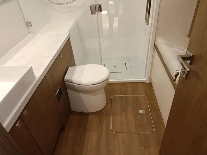  Yacht Photos Pics Modern bathroom in 2022 Mazarin 55 Catamaran, featuring wood flooring and sleek fixtures.