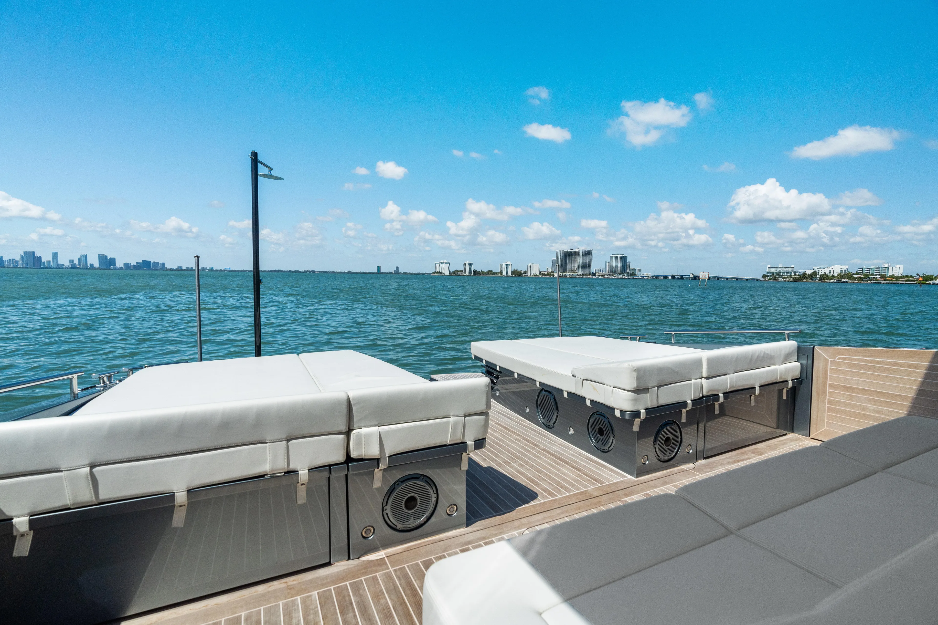 Pura Vida Yacht Photos Pics 2024 CNM CONTINENTAL 54 SuperSport yacht deck with sunbeds, overlooking ocean and city skyline.