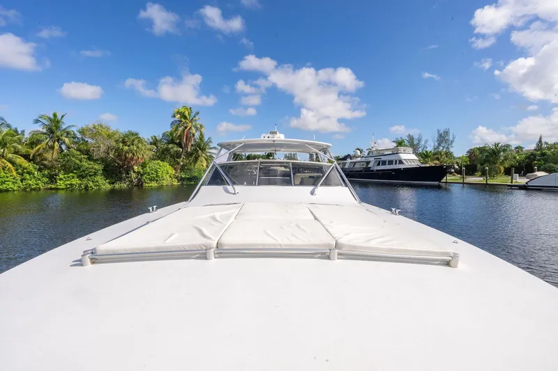 Prana Yacht Photos Pics 1995 Itama 46 yacht on a serene waterway with lush greenery and blue sky.