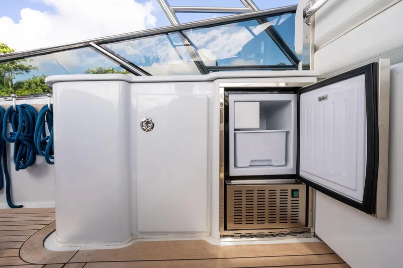 Prana Yacht Photos Pics Itama 46 yacht (1995) with open mini fridge on deck, blue ropes, and glass railing.