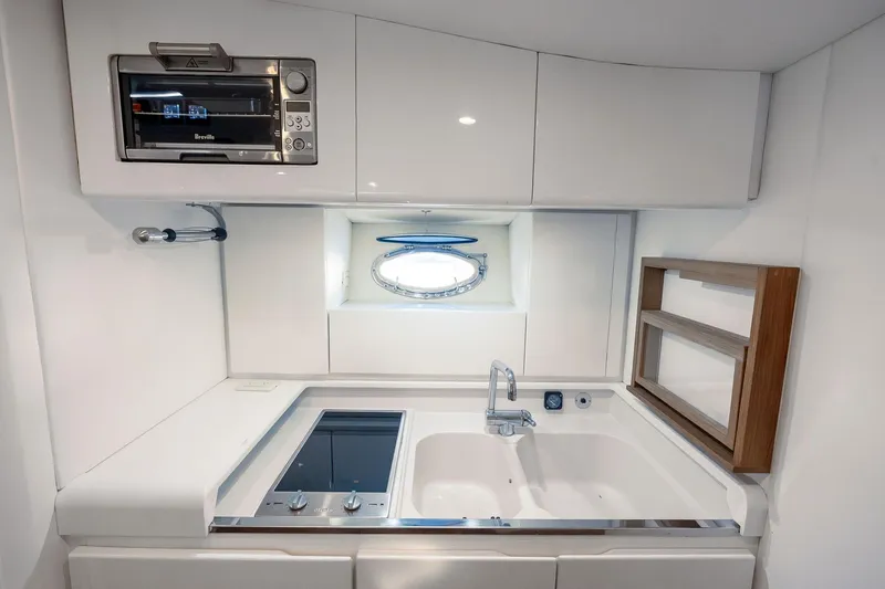 Prana Yacht Photos Pics Compact kitchen area in a 1995 Itama 46 yacht with modern appliances and porthole window.