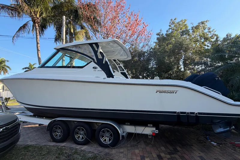  Yacht Photos Pics 2017 Pursuit DC 295 Dual Console boat on trailer, surrounded by palm trees.
