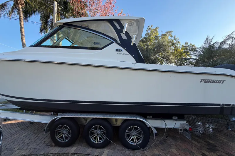  Yacht Photos Pics 2017 Pursuit DC 295 Dual Console boat on trailer, surrounded by trees.