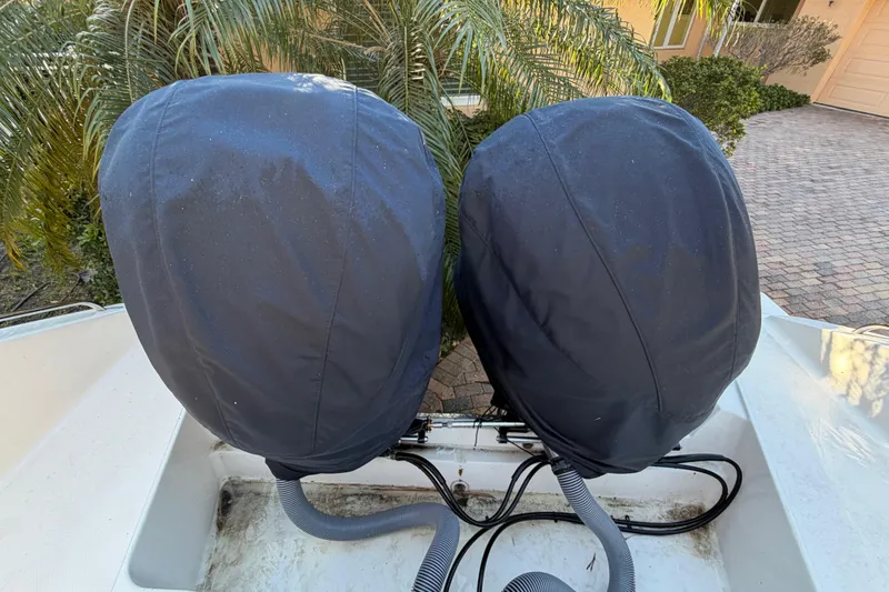  Yacht Photos Pics Covered engines on a 2017 Pursuit DC 295 Dual Console boat, parked near palm trees.