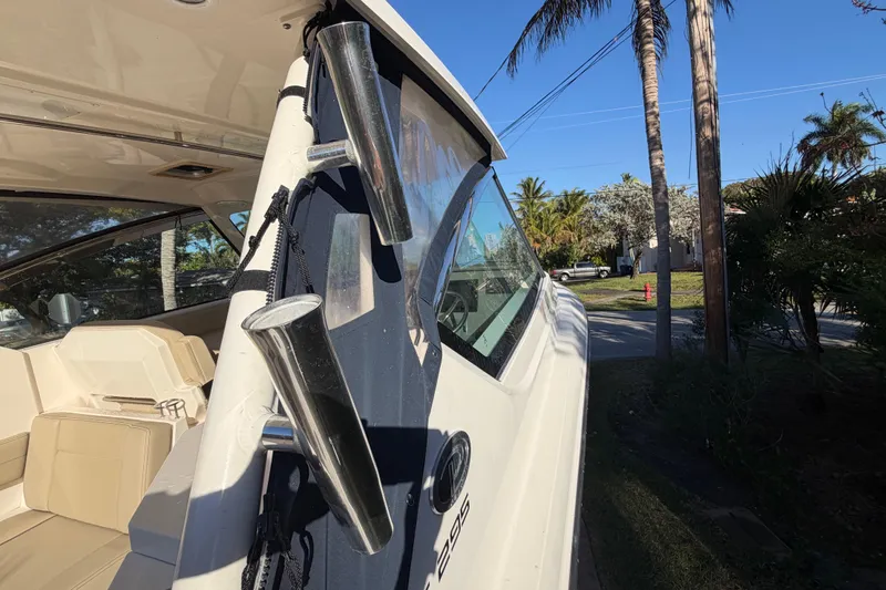 Yacht Photos Pics 2017 Pursuit DC 295 Dual Console boat with rod holders, parked near palm trees.