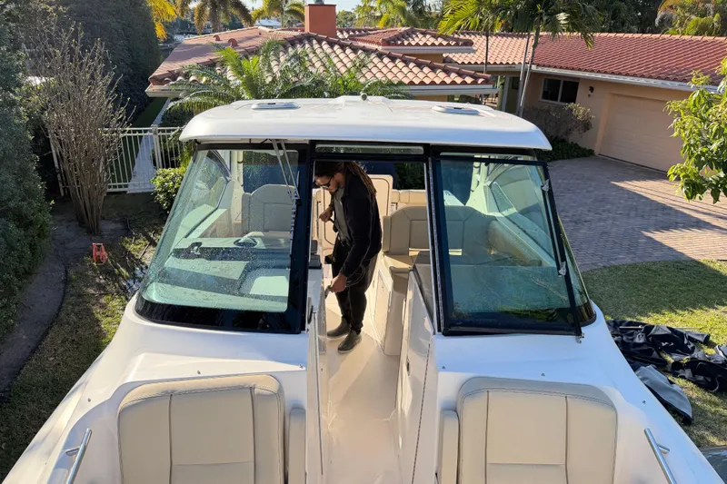  Yacht Photos Pics 2017 Pursuit DC 295 Dual Console boat parked near a house with a person onboard.