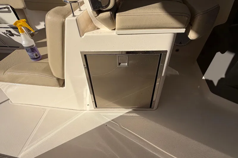  Yacht Photos Pics 2017 Pursuit DC 295 Dual Console interior with storage compartment and cleaning spray bottle.