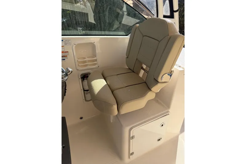  Yacht Photos Pics 2017 Pursuit DC 295 Dual Console boat seat with beige upholstery and storage compartment.