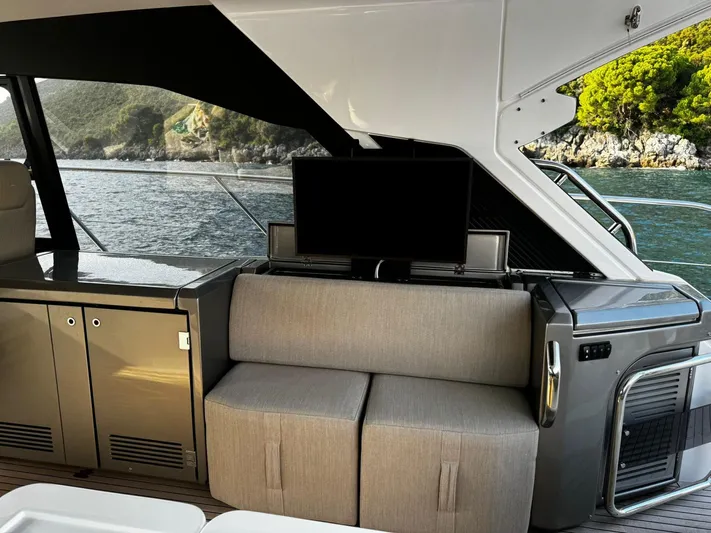  Yacht Photos Pics Interior of 2022 Azimut Atlantis 51 yacht with seating and TV, overlooking scenic coastline.