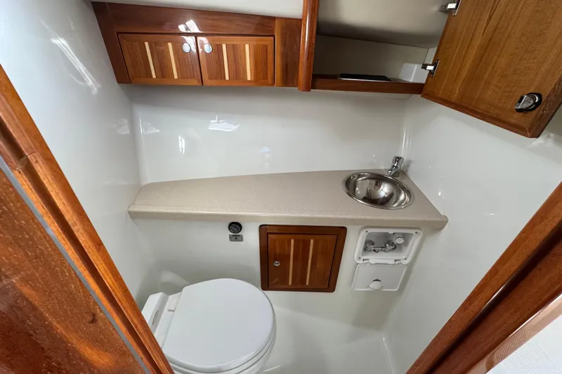  Yacht Photos Pics Compact bathroom in 2005 Ocean Sport Roamer 30 boat with wooden cabinets and stainless steel sink.