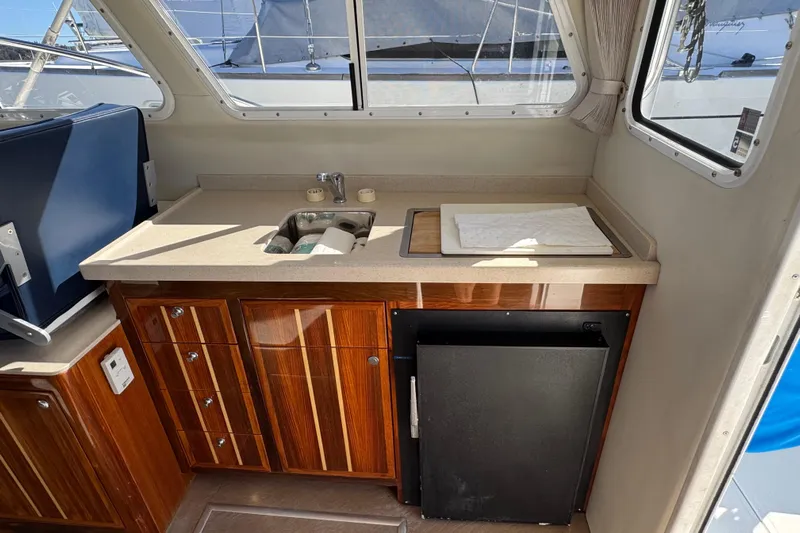  Yacht Photos Pics 2005 Ocean Sport Roamer 30 interior with kitchenette, sink, and wooden cabinetry.
