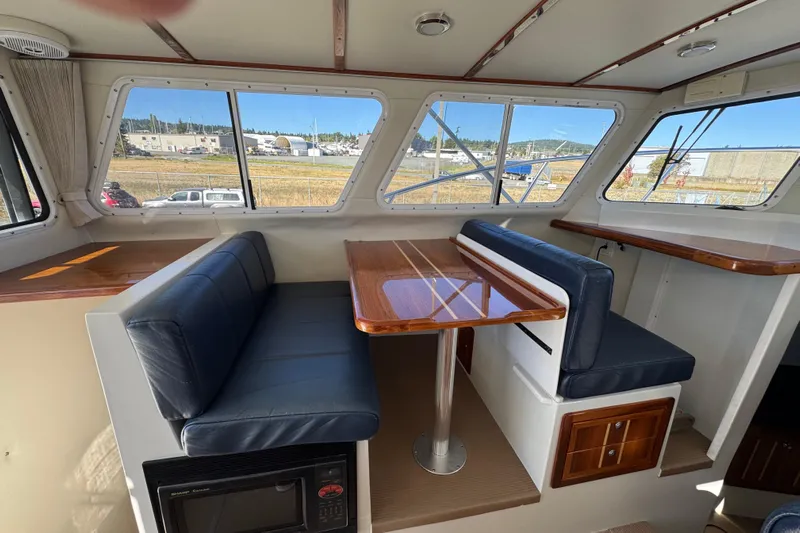  Yacht Photos Pics Interior of 2005 Ocean Sport Roamer 30 with blue seating and wooden table.