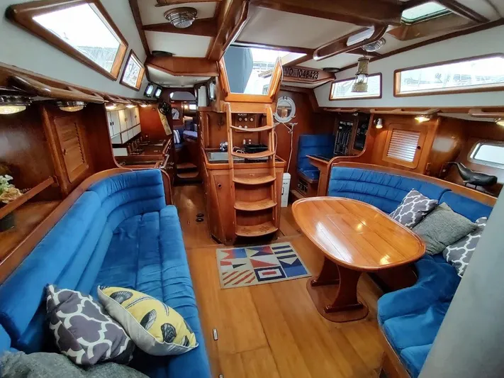 Trinity Yacht Photos Pics Luxurious interior of a 1997 Hylas 46 yacht with blue seating and wooden finishes.