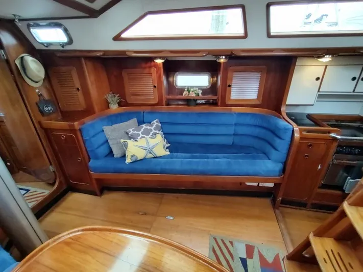 Trinity Yacht Photos Pics Interior of 1997 Hylas 46 yacht with blue cushioned seating and wooden cabinetry.