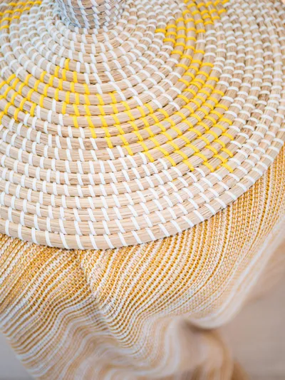 Blessed Yacht Photos Pics Woven basket lid with yellow and white patterns on a striped textile background.