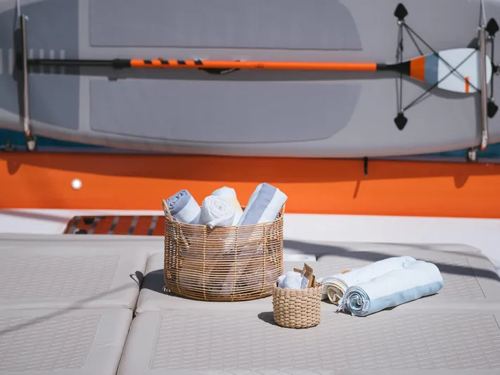 Blessed Yacht Photos Pics Basket of towels on Sunreef 50 A yacht deck, 2024 model, with paddleboard in background.