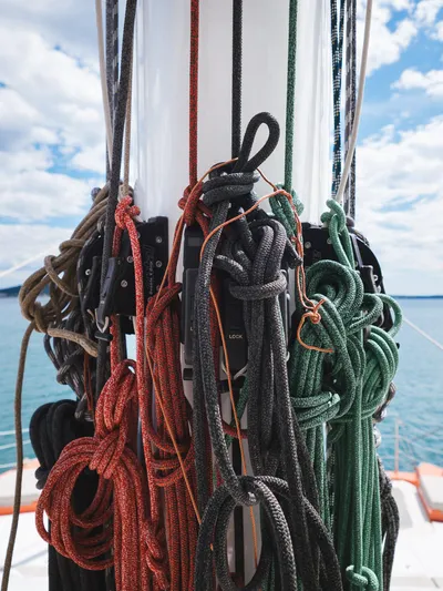 Blessed Yacht Photos Pics Colorful ropes on Sunreef 50 A yacht mast, 2024 model, against a blue sky and sea backdrop.