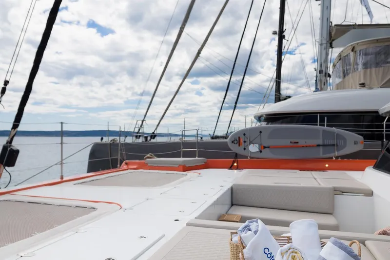 Blessed Yacht Photos Pics 2024 Sunreef 50 A yacht deck with paddleboard, under a cloudy sky.