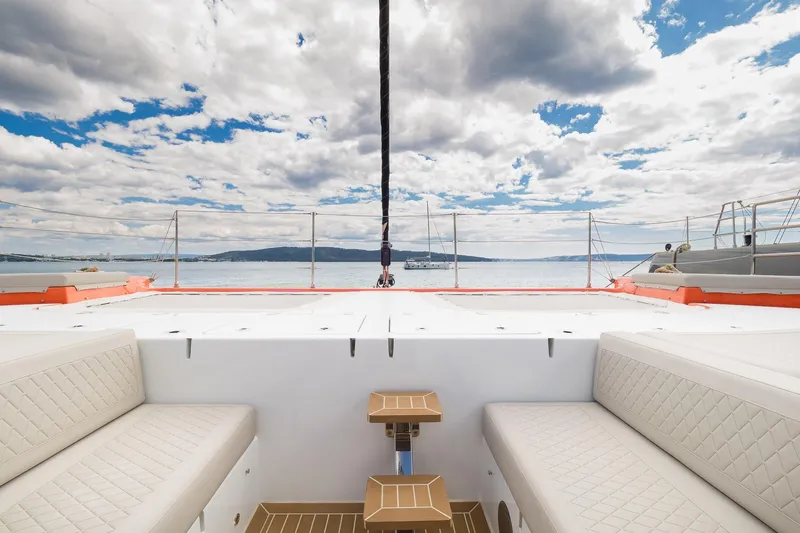 Blessed Yacht Photos Pics 2024 Sunreef 50 A yacht deck with seating, overlooking calm sea and cloudy sky.