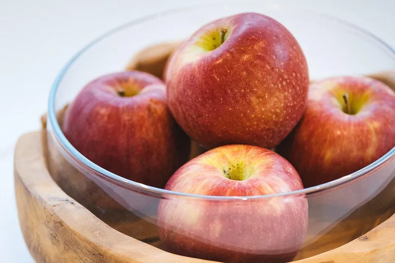 Blessed Yacht Photos Pics A glass bowl filled with fresh red apples on a wooden base.