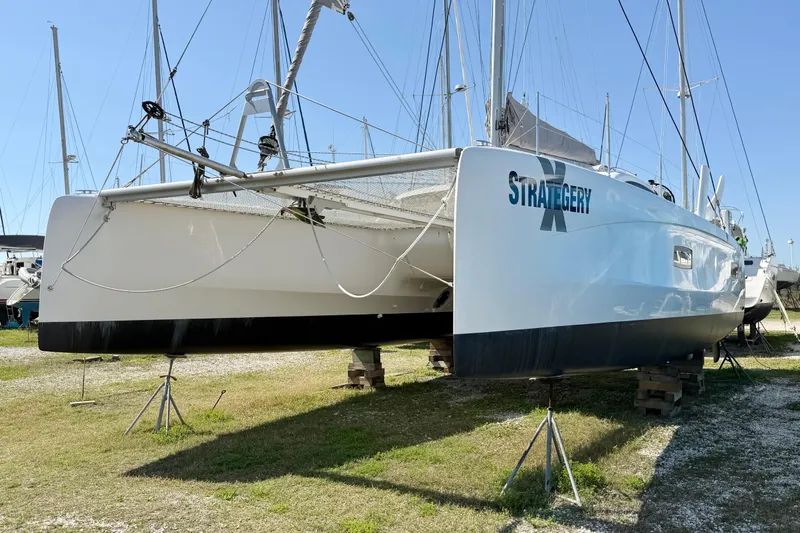 Strategery X Yacht Photos Pics 2014 Outremer 45 catamaran on land, named "Strategery X," under clear blue sky.