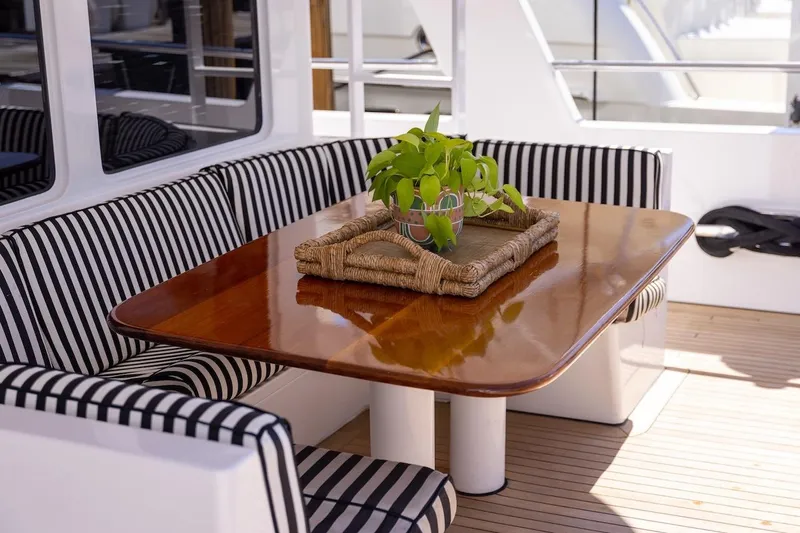  Yacht Photos Pics Luxury yacht interior with striped seating, wooden table, and decorative plant, ABD 90 Explorer 1996.