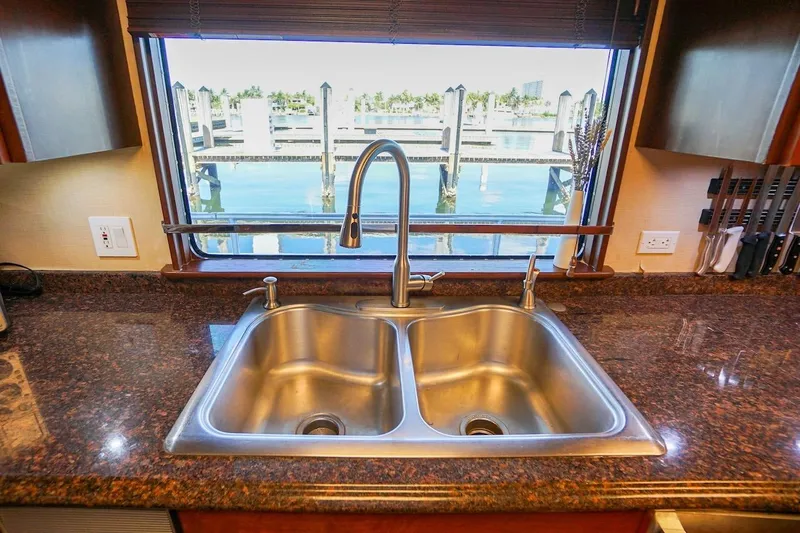  Yacht Photos Pics Stainless steel double sink on granite countertop with marina view through window.