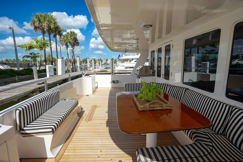  Yacht Photos Pics Luxurious 1996 ABD 90 Explorer yacht deck with striped seating and wooden table.