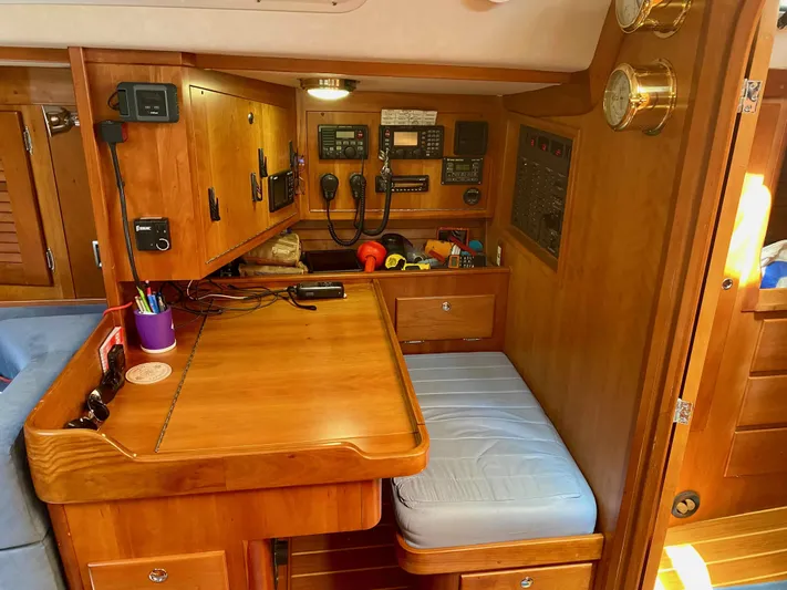 Navicula Yacht Photos Pics Navigation station inside 2001 J Boats J/46, featuring wooden cabinetry and communication equipment.
