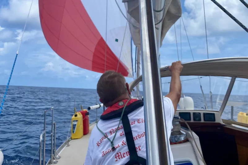 Navicula Yacht Photos Pics Man sailing a 2001 J Boats J/46 with red spinnaker on open ocean.