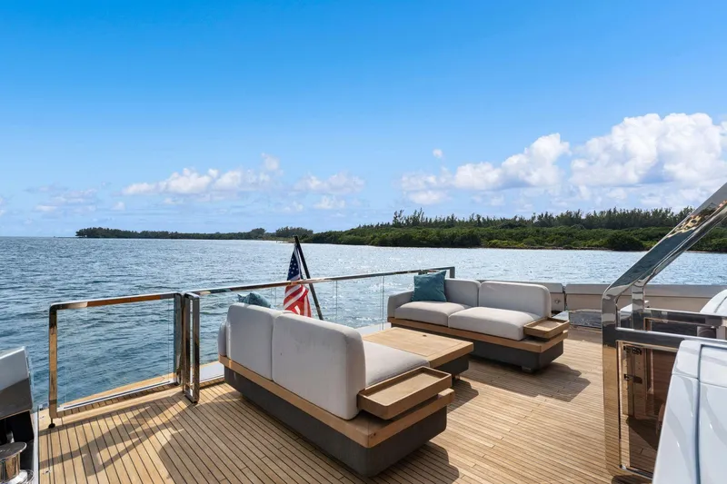 Latitude Yacht Photos Pics Luxurious 2022 Azimut S10 yacht deck with elegant seating, overlooking serene ocean and lush coastline.