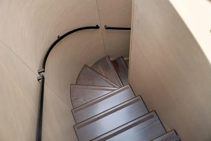 Latitude Yacht Photos Pics Curved wooden staircase on 2022 Azimut S10 yacht with sleek black handrails.