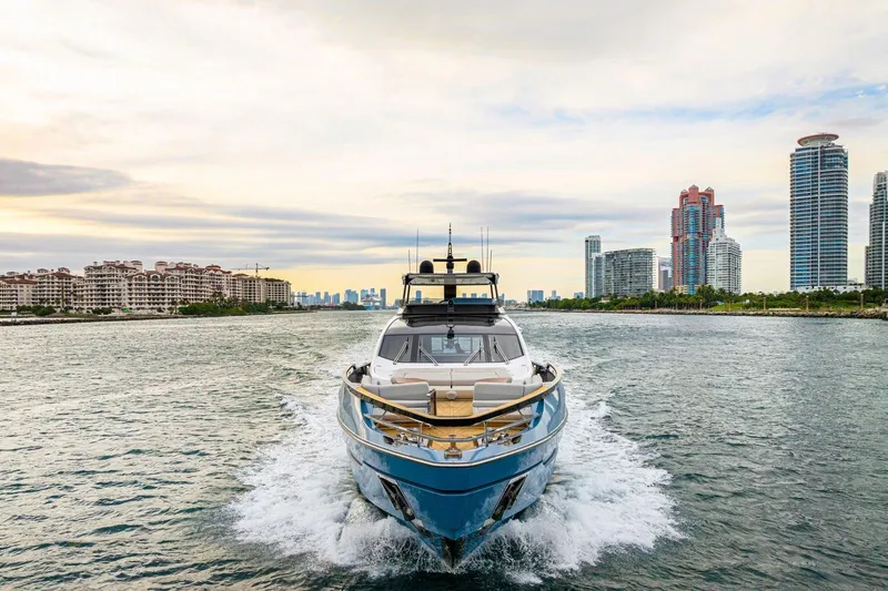 Latitude Yacht Photos Pics 2022 Azimut S10 yacht cruising near city skyline under a cloudy sky.