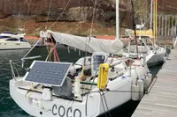 2020 Dehler 30 sailboat docked, featuring solar panel and scenic rocky backdrop.
