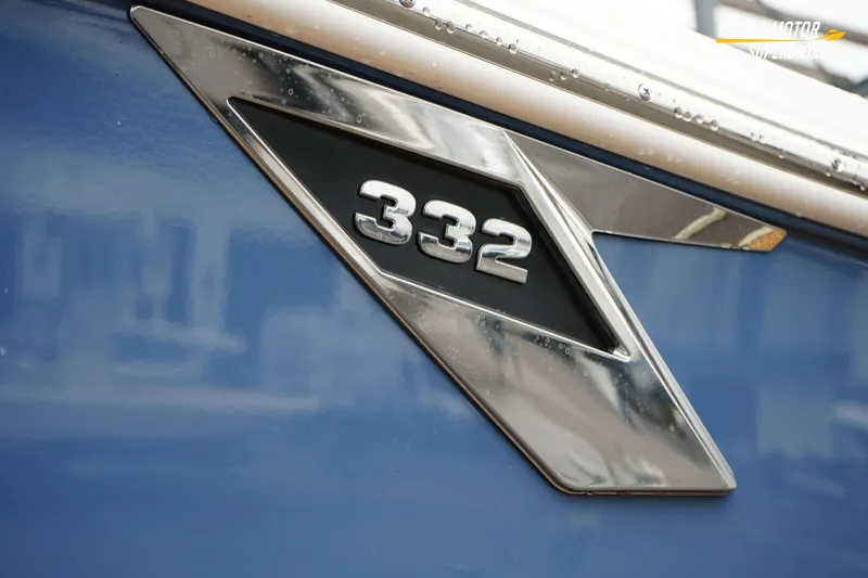  Yacht Photos Pics 2026 Blackfin 332 CC boat emblem on blue hull, showcasing sleek design.