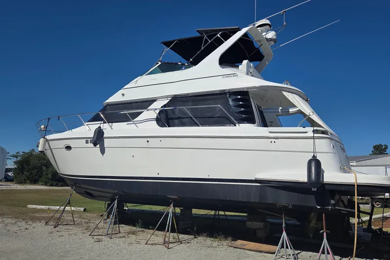 Pier Pressure Yacht Photos Pics 2000 Carver 450 Voyager Pilothouse yacht on stands, clear blue sky background.