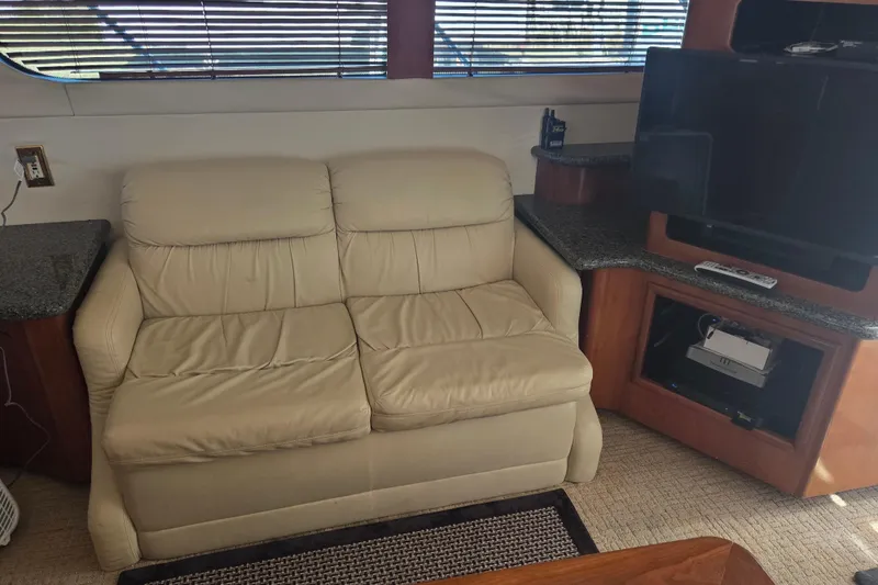 Pier Pressure Yacht Photos Pics Interior of 2000 Carver 450 Voyager Pilothouse with beige sofa and TV setup.