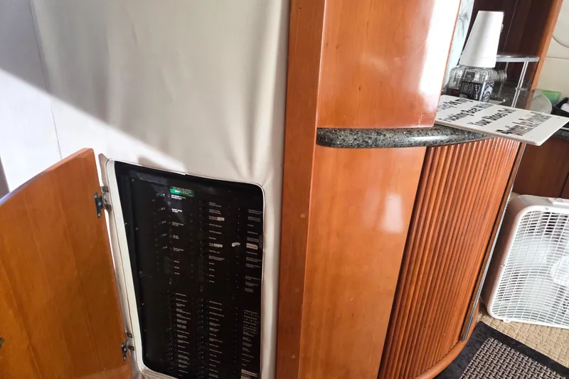 Pier Pressure Yacht Photos Pics Interior of 2000 Carver 450 Voyager Pilothouse with open electrical panel and wooden cabinetry.