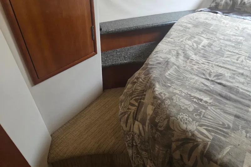 Pier Pressure Yacht Photos Pics Interior of 2000 Carver 450 Voyager Pilothouse with bed, steps, and wooden cabinet.