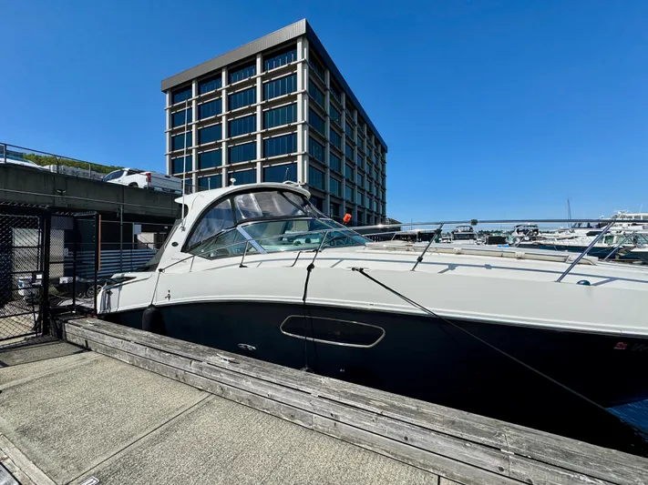 Pendragon Yacht Photos Pics 2009 Sea Ray 350 Sundancer docked near a modern building under clear blue skies.