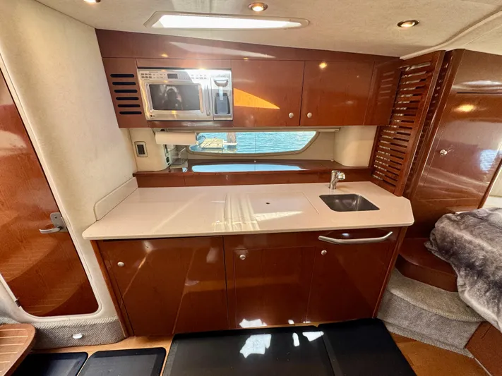 Pendragon Yacht Photos Pics 2009 Sea Ray 350 Sundancer interior kitchen with microwave, sink, and wooden cabinetry.