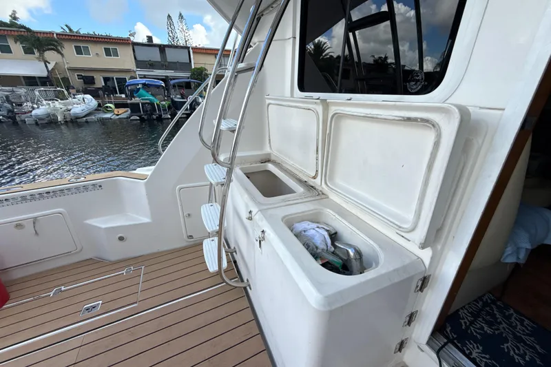  Yacht Photos Pics 2003 Riviera 37 Flybridge yacht deck with storage compartments and ladder, docked by waterfront homes.