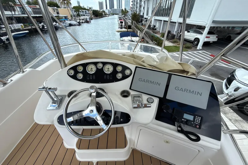  Yacht Photos Pics 2003 Riviera 37 Flybridge helm with Garmin displays and steering wheel, docked by a canal.