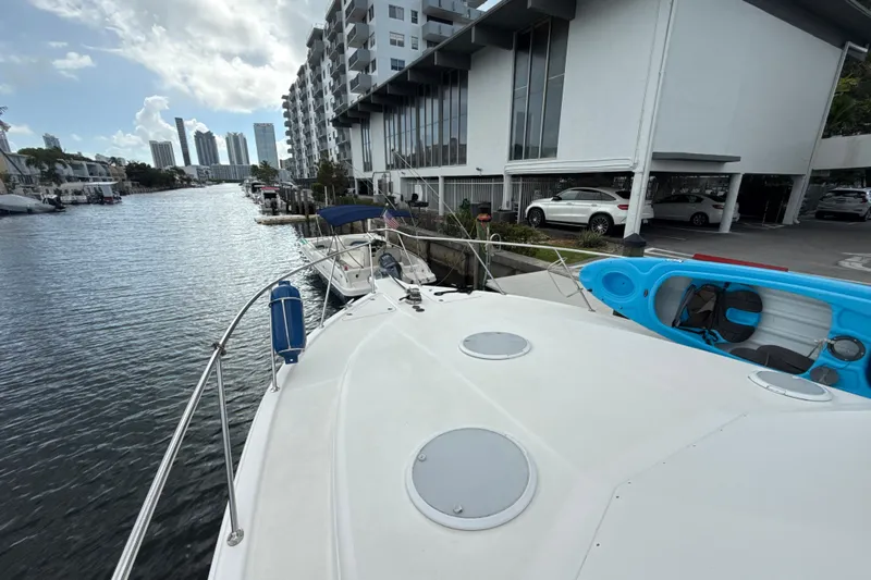  Yacht Photos Pics 2003 Riviera 37 Flybridge docked by waterfront buildings, with kayak on deck.