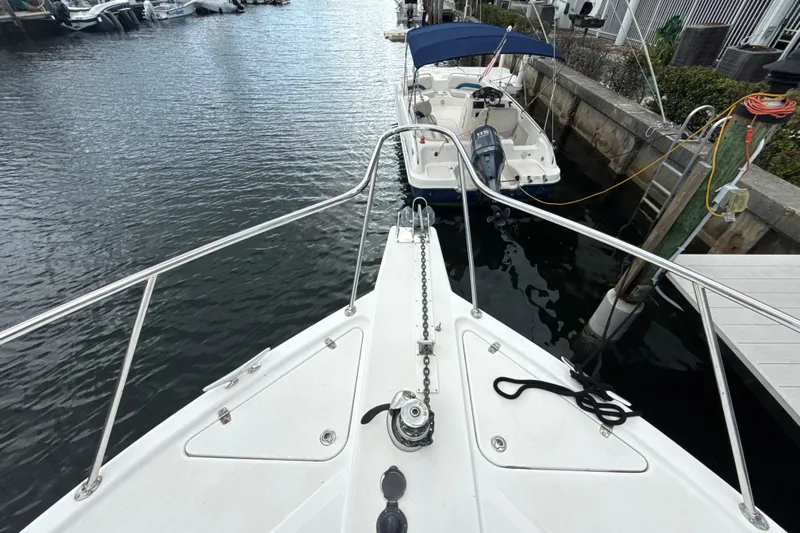  Yacht Photos Pics Bow view of 2003 Riviera 37 Flybridge yacht docked near a smaller boat.