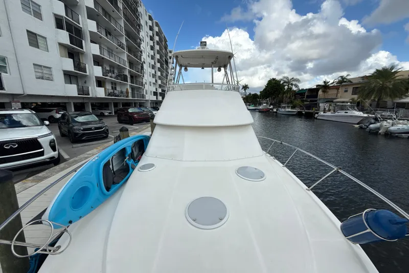  Yacht Photos Pics 2003 Riviera 37 Flybridge yacht docked near waterfront apartments, with a blue kayak on deck.