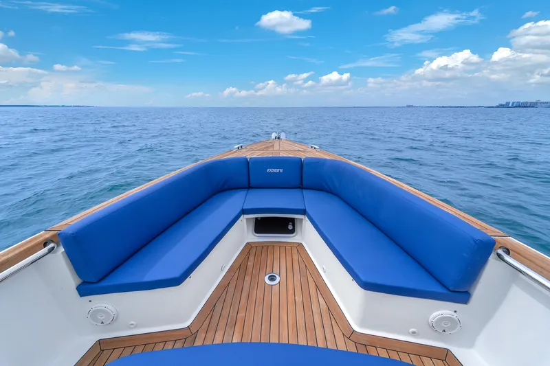 No Name Yacht Photos Pics Bow of 2019 Fjord 38 boat with blue seating, on open sea under clear sky.