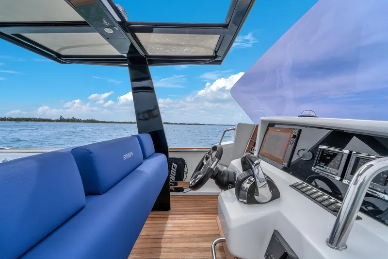 No Name Yacht Photos Pics 2019 Fjord 38 boat interior with blue seating, modern dashboard, and scenic ocean view.